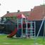 Maikäfer Spielturm mit Kletterwand, Rutsche und Schaukeln im Garten.