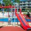 Kinder spielen auf einem Spielplatz mit der Spielanlage Walfisch, bestehend aus Rutsche und Kletterg
