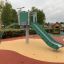 Krähennest Kletterturm mit Rutsche auf einem bunten Spielplatz.