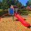 Krähennest Kletterturm mit roter Rutsche und blauen Wänden auf einem Spielplatz.