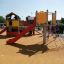 Kinder spielen auf einem Krähennest Kletterturm mit Rutsche auf einem Spielplatz.