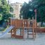 Schiff-förmiger Sandkasten mit Rutsche und Kletternetz aus Robinienholz auf einem Spielplatz.