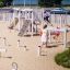 Kinder spielen auf einem Spielplatz mit Alstad Spielkombination mit Rutsche am sonnigen Tag.