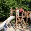 Kinder spielen auf einer Alstad Spielkombination mit Rutsche auf einem Spielplatz.