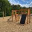 Holzspielplatz Alstad Spielkombination mit Rutsche und Kletterelementen auf Hackschnitzeln.