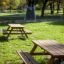 Holzbank und -tisch aus Lärche im Park, sonniger Tag.