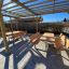 Holztische und Bänke unter einem Pergola aus Lärcheholz und verzinktem Stahl in einem sonnigen Garte