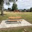 Lärchenholz Bank und Tisch auf gepflasterter Fläche in einem Park, im Hintergrund Spielplatz
