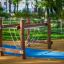 Kongo Wackelbrücke auf einem Kinderspielplatz mit blauer Sicherheitsmatte und grünem Rasen im Hinter