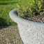 Blumentopf Bell aus Beton im Freien mit Zierpflanzen und Kieselsteinboden.
