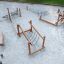 Sahara Trimm-dich-Pfad Spielplatz aus Holz mit Kletter- und Balanciergeräten auf Sandboden.