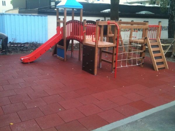 Spielplatz mit roter Rutsche und Fallschutzplatte 110 auf einem Spielbereich im Freien.