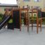 Spielplatzgerät Wetpour 60 mit Rutsche und Kletterelementen in einem Gartenbereich.