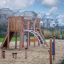 Holzspielplatz Madagascar (5 St.) mit Rutsche und Klettermöglichkeiten auf einem Sandboden.