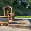 Villa Spielhaus mit Sandkasten aus Holz im Garten.