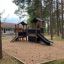 Holzspielhaus Schloss mit Rutsche und Kletterwand im Freien auf einem Spielplatz.
