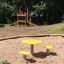 Spieltisch und Stuhl mit gelben Sitzen im Freien neben einem Spielplatz