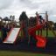 Kinder spielen auf Berlin Spielanlage mit Spielturm und Rutschen im Park.