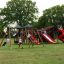 Kinder spielen auf Berlin Spielanlage mit Spielturm und Rutschen im Park.