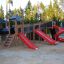Spielplatz mit Berlin Spielanlage, zwei roten Rutschen und Kletterturm in einem Sandbereich.
