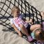 Kinder spielen in einer schwarzen Hängematte Robinie am Strand.
