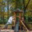 Spielturm mit Kletterwand, Rutsche und Kletternetz im Herbstpark.