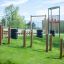 Einzelreck Robinie auf grünem Rasen mit Hintergrundspielplatz und Balanceelementen.