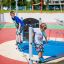 Zwei Kinder spielen auf einem Wonderland Trimm-dich-Pfad auf einem bunten Spielplatz.