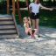 Kind auf der Seilbahn Mittel mit Plattform auf dem Spielplatz, begleitet von einer Frau.