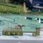 Luftbild eines Spielplatzes mit Seilbahn Mittel und Plattform, umgeben von Grünflächen.