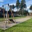 Seilbahn Mittel mit Plattform auf Spielplatz, umgeben von Bäumen und Sandboden.
