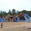 Bounty Spielschiff mit Tunnel und Rutsche auf einem Kinderspielplatz in Sandumgebung, belebt mit spi