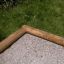 Fünfeckige Sandkastenumrandung aus Holz auf grünem Rasen.