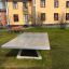 Freistehende Betontischtennisplatte im Außenbereich eines Gebäudekomplexes.