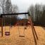 Doppeltes Schaukelgestell aus Holz auf Spielplatz mit Rindenmulch Boden.