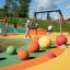 Kinder spielen auf einem Spielplatz mit Schaukel Rahmen (Doppelt) und bunten Bällen.