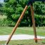Einzelne Schaukel mit rotem Sitz und Holzrahmen im Garten.