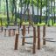 Kinderspielplatz mit Kentucky Doppelt Balanciergerät und Hintergrund mit Bäumen und einer Schaukel.
