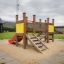 Spielplatzgerät Der Knirps Turm mit Rutsche in einem Outdoor-Bereich mit Sandboden.