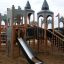 Schloss Windsore Spielplatz mit Spieltürmen, Rutsche und Kletternetz auf Sandboden.
