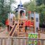 Schloss Camelot Spieltürme mit Rutsche und Kletterwand auf einem Spielplatz umgeben von Bäumen.