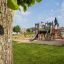 Holzspielplatz Schloss Camelot mit Rutsche und Klettermöglichkeiten im Freien.