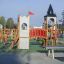 Kleine Schloßbrücke Spielturm mit Rutsche auf einem Spielplatz in urbaner Umgebung.