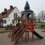 Kleine Schloßbrücke Spielturm mit Rutsche vor einem Wohnhaus, ideal für Kinder.