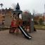 Kleine Schloßbrücke Spielturm mit Rutsche auf einem Spielplatz, umgeben von Grünflächen.