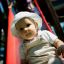 Kleines Kind rutscht auf roter Rutsche im Spielplatz.
