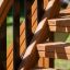 Nahaufnahme der Holzleiter eines Spielturms mit Rutsche im Freien.