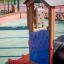Kinderspielplatz mit Rutsche und Lernpanel in einem Park.