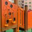 Smart Spielanlage mit Rutsche und Kletterspiel in lebendigem Orange auf einem Spielplatz.