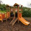 Kinderspielplatz mit Rutsche, Kletterwand und Spielhaus im Freien.